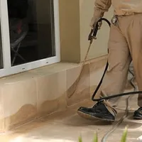 General pest control technician spraying exterior perimeter around a home in Hollywood, FL