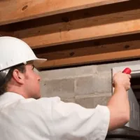 Termite inspection technician checking a basement wall and framing for termite activity in Hollywood, FL